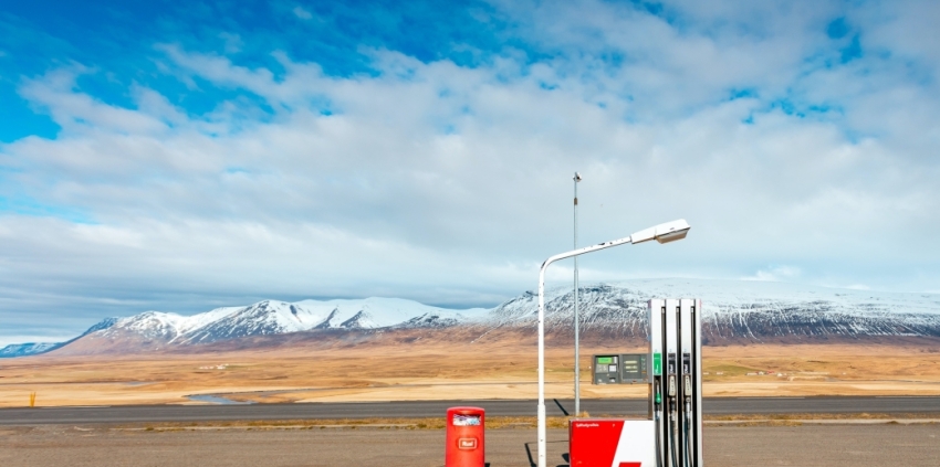 A single fuel pump with a blue sky and clouds above the mountains in the background.