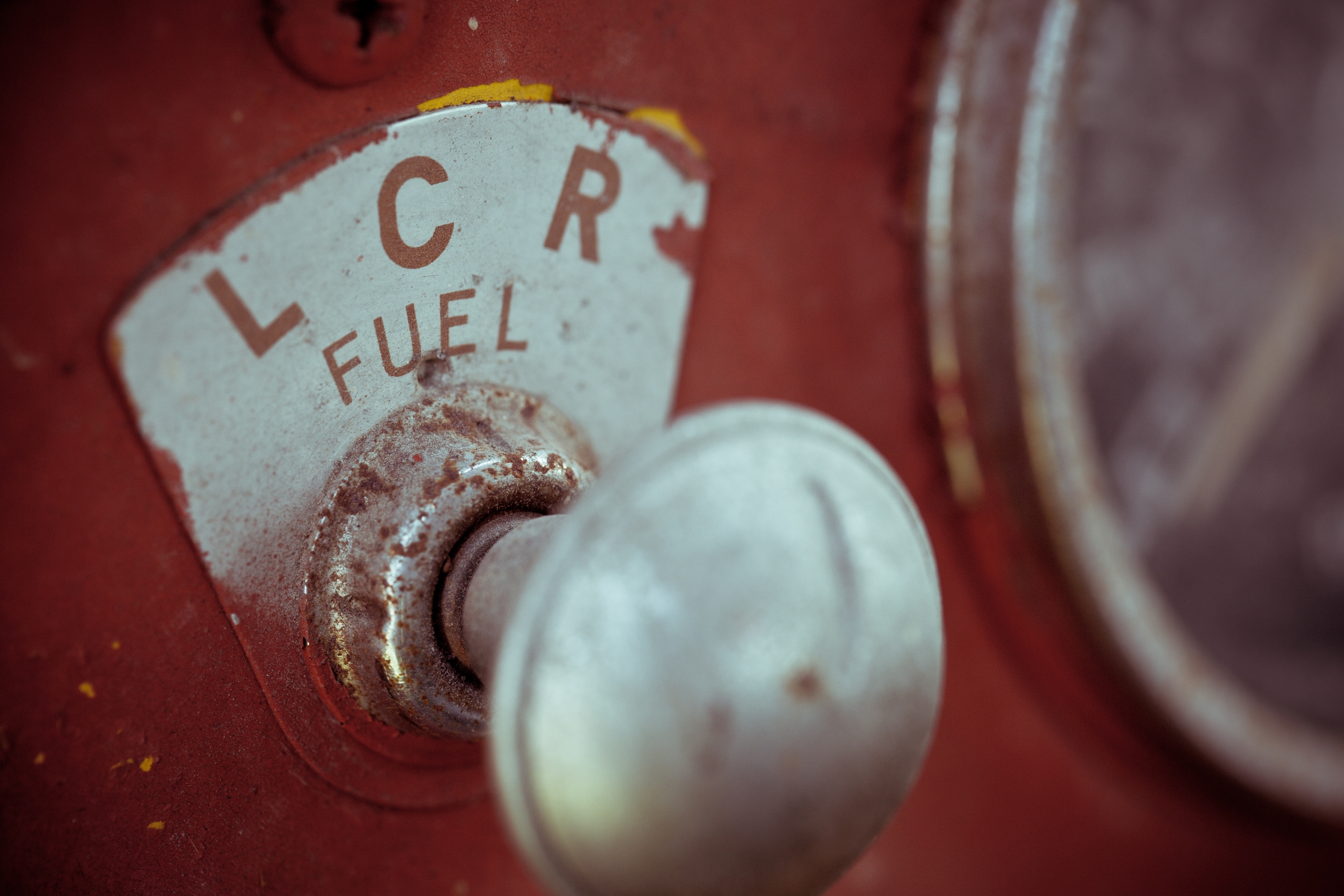 Silver lever in a red dashboard with letters spelling "fuel" above is and the letters "L, C, R" about Fuel.
