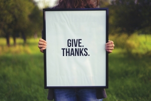 give thanks on white sign held in front of a person