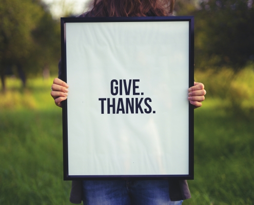 give thanks on white sign held in front of a person; sharing gratitude