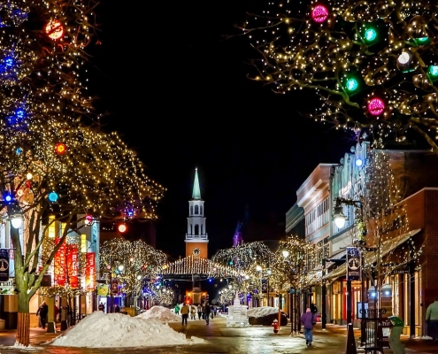 image of traditional small town main street lit with Christmas lights with church at the end of the street - connection