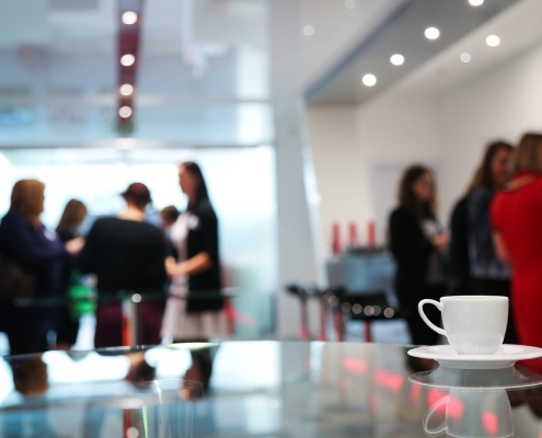 image of coffee cup on table with lots of people in background,; conference, event