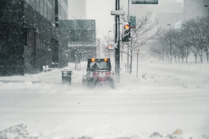 city scene with heavy snowfall and a street-cleaning truck blurred from snowfall; preparing for winter
