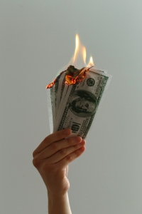 hand holding money that is on fire; hedging - identifying risks