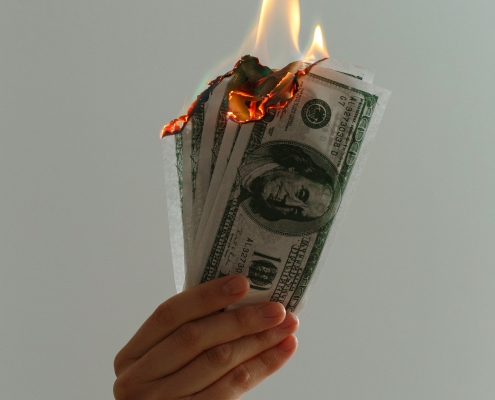 hand holding money that is on fire; hedging - identifying risks