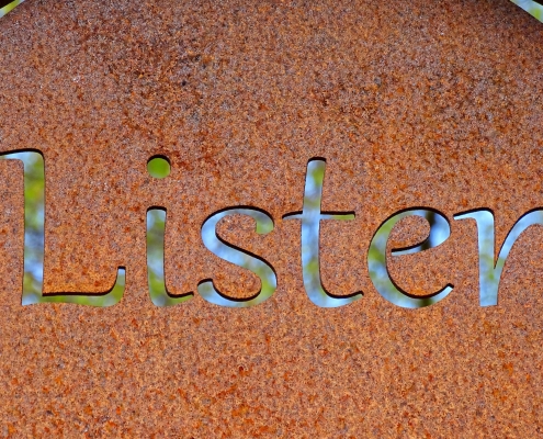 rusted sign with the word listen cut out of it