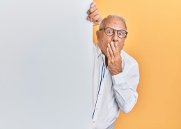 older man with glasses peaking around corner looking surprised; market news; tariffs