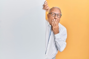 older man with glasses peaking around corner looking surprised; market news