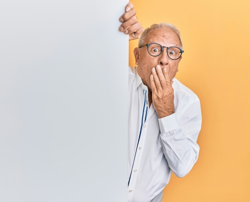 older man with glasses peaking around corner looking surprised; market news