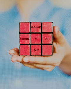 image of a hand holding a rubik's cube, red side facing out, with the words 
