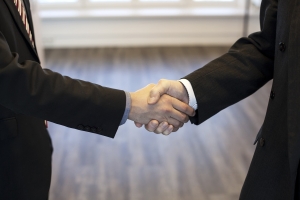 image of two hands clasped in business dress; demonstrating merging