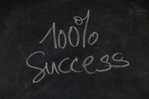 blackboard with 100% success written in chalk on it; Beyond Expectations