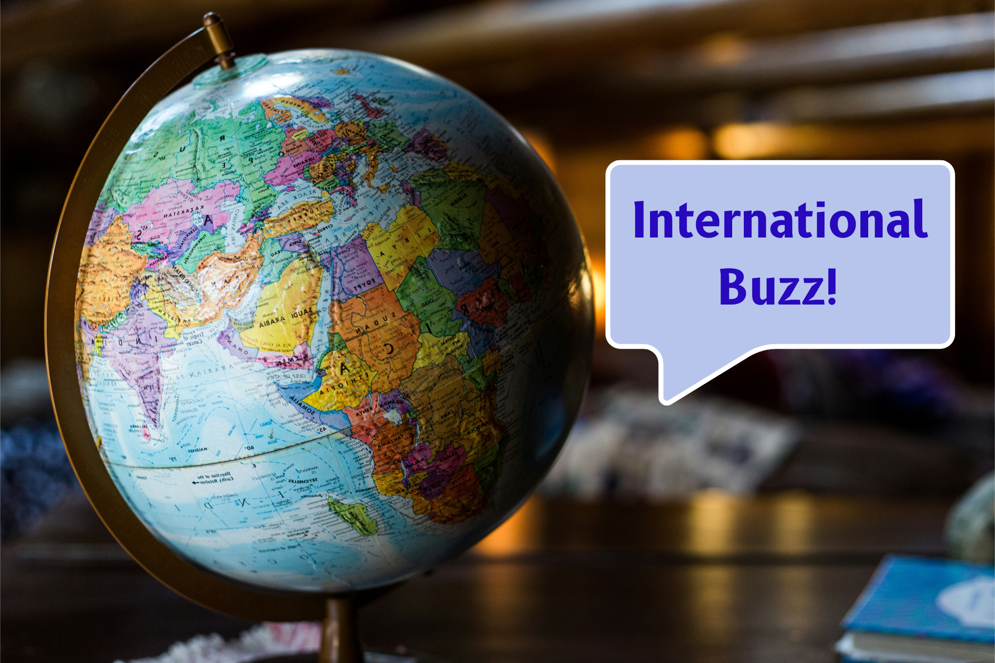 globe with a speech bubble saying International Buzz! against a blurred background