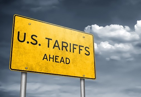 yellow road sign against a blue sky with the words U.S. Tariffs ahead